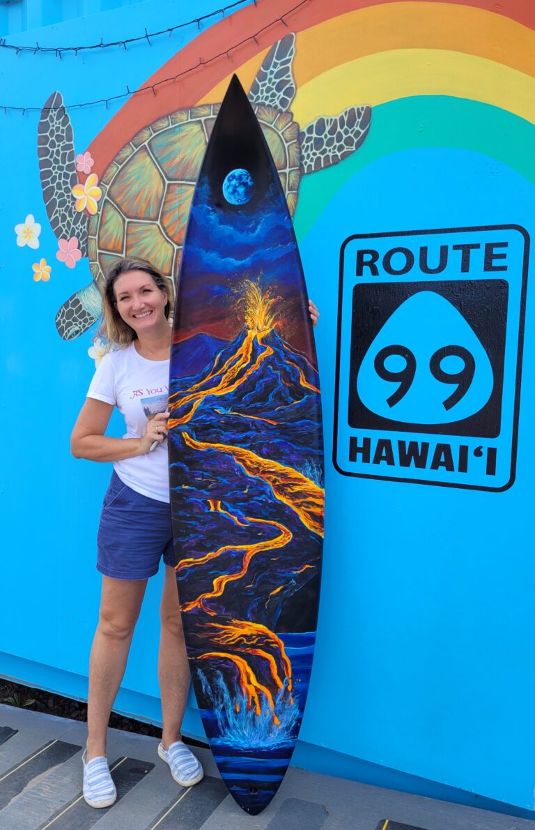 The artist stands next to a painted surfboard showing a Hawaiian Volcano erupting