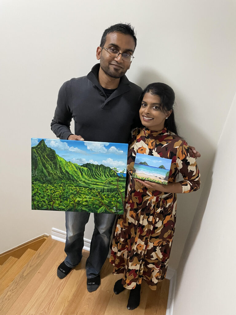 a photo of two happy customers holding up their paintings from As You Wish Arts